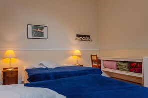 Two beds with comfortable bedding, a wardrobe, and a coat rack.