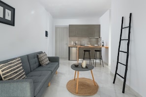 Un salon moderne avec un canapé gris, une petite table ronde et un tapis tissé.