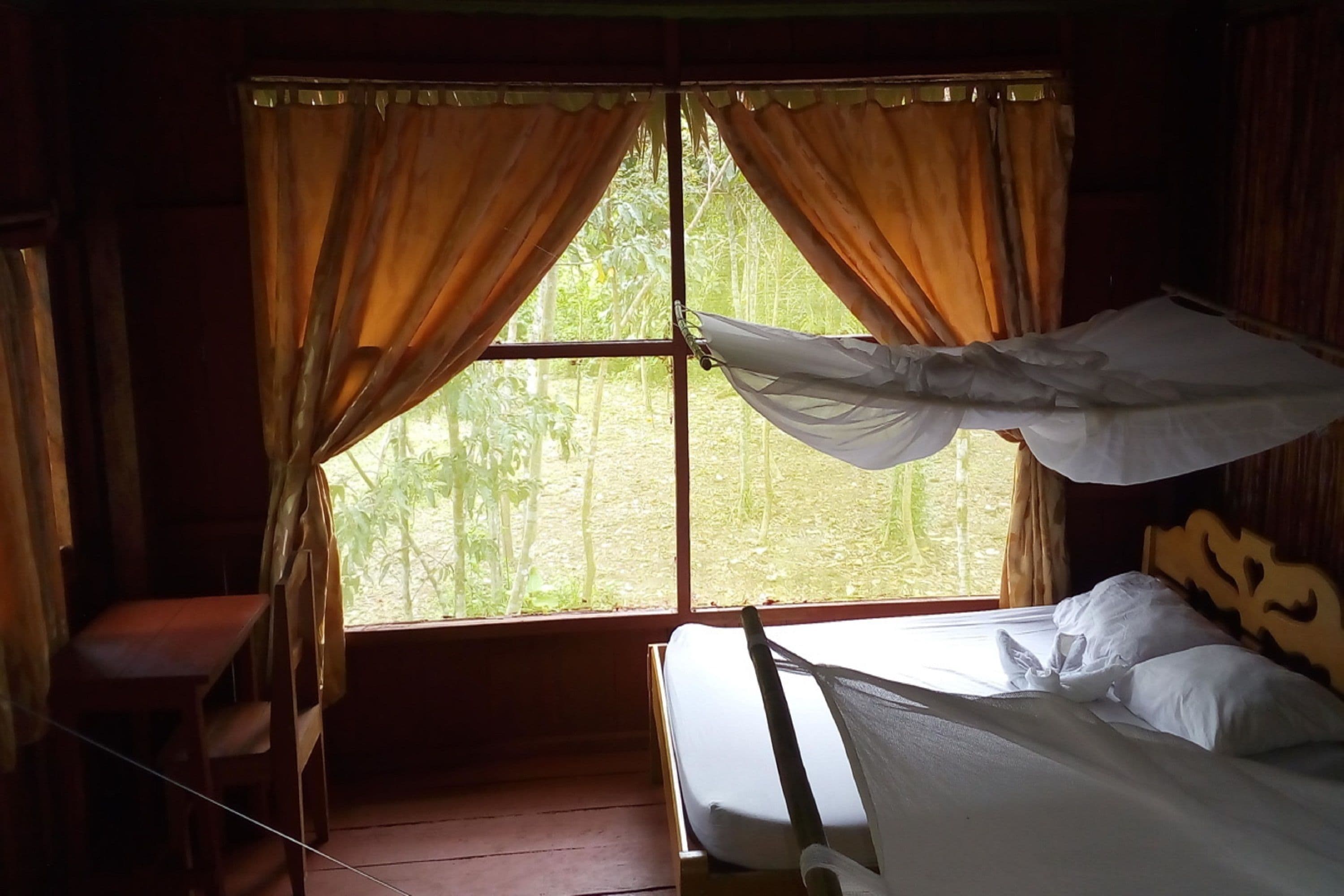 A room with a bed, a chair, and a window with curtains.