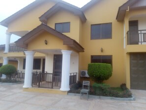 A two-story building with a yellow facade, white columns, and a balcony. - Bezt Executive Guesthouse (Accra)
