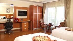 A hotel room with a bed, a desk with a chair, a wardrobe, a TV, and a window with curtains. - Emmad Apartment Hotel (Addis Ababa)