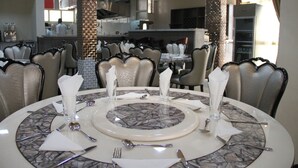 A dining area with round tables set for four, each with a marble-patterned table runner, white napkins, and silverware. - Emmad Apartment Hotel (Addis Ababa)