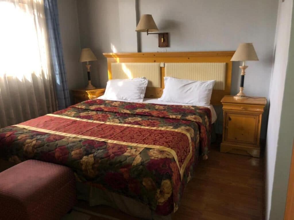 A hotel room with a large bed, two bedside tables, a nightstand, and a chair.