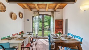 Un espace repas doté d’un plafond en bois, d’une grande fenêtre donnant sur un paysage verdoyant et d’une porte.