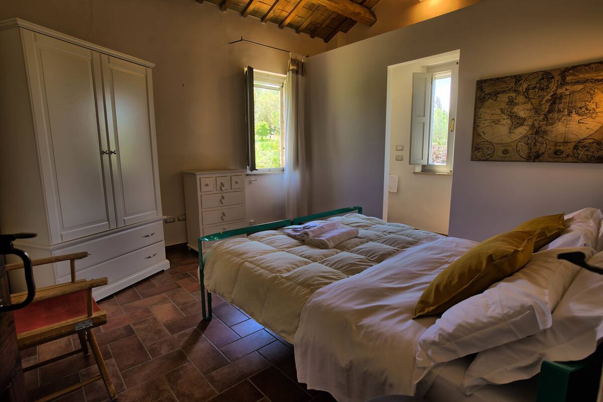 A bedroom with a bed, a wardrobe, a dresser, and a window.