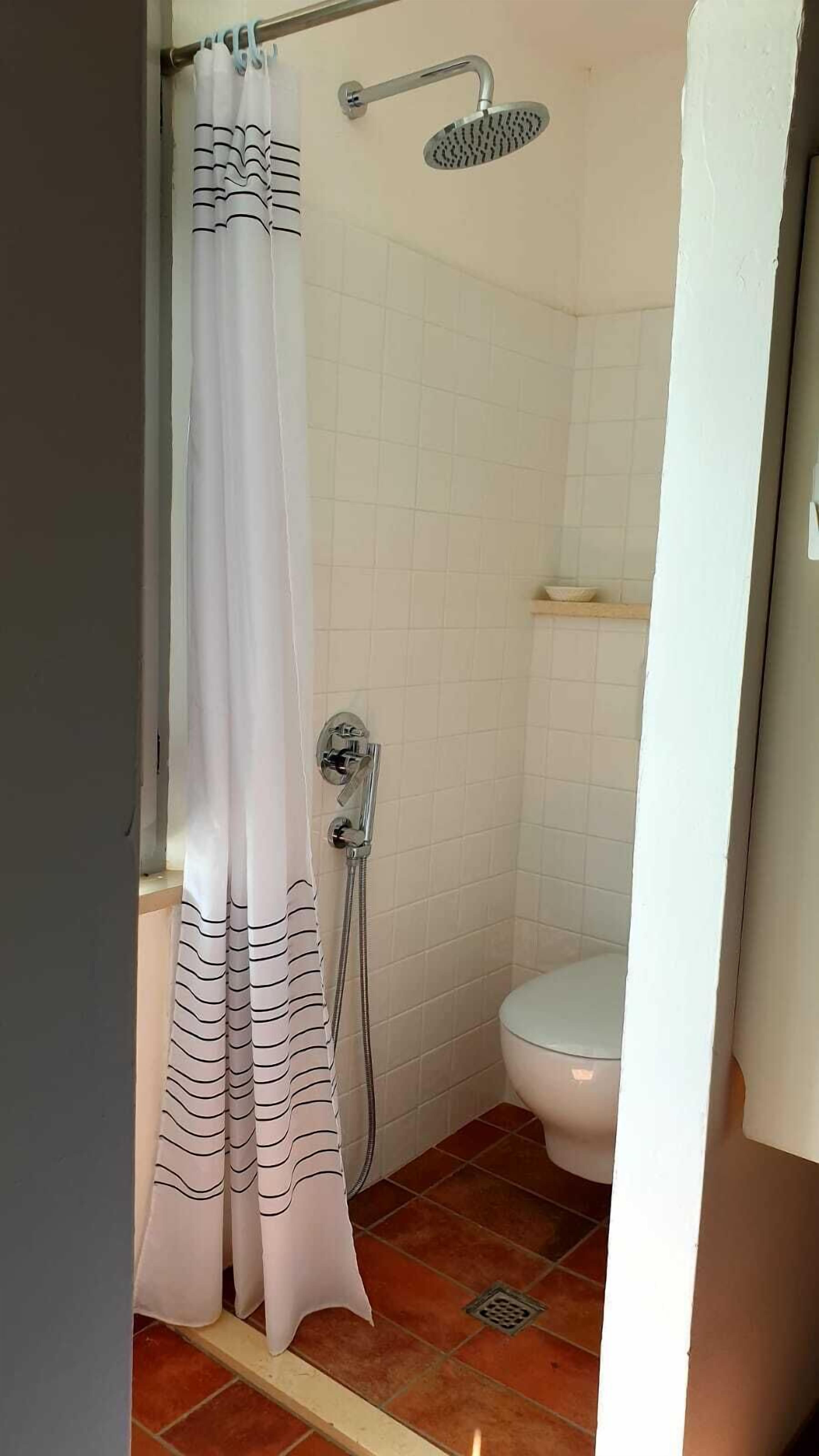 A bathroom with a shower, toilet, and tiled walls.