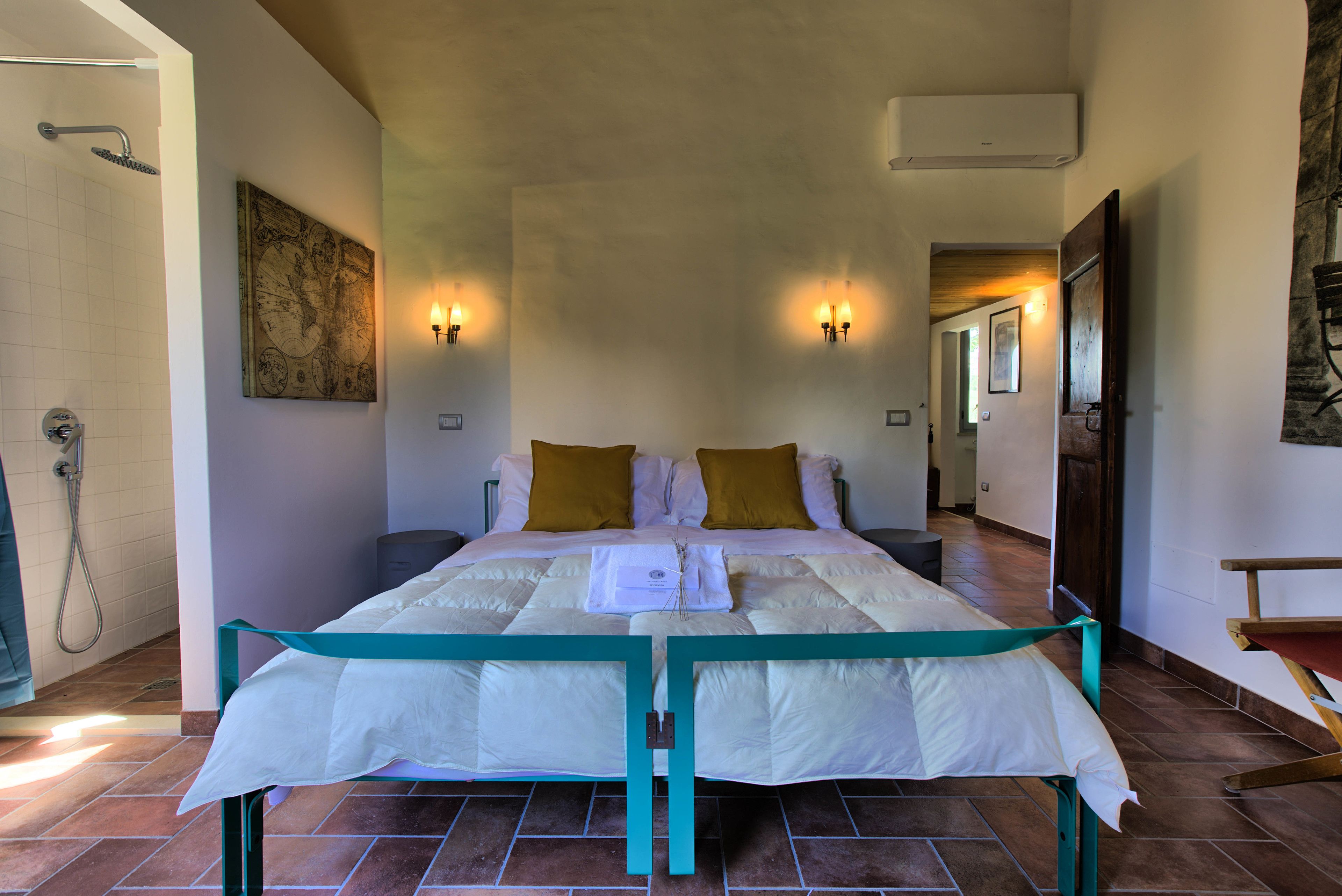 A spacious bedroom with a large bed, a map on the wall, and a shower area.