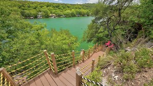 Un ponte di legno con corde gialle che conduce a un lago circondato da alberi.