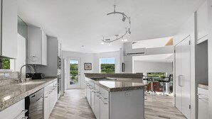 Una cucina moderna con mobili bianchi, piani in granito e un'isola centrale.