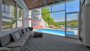 Una terrazza moderna all'aperto con piscina, ampie finestre e vista sul paesaggio.