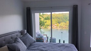 Una camera da letto con un letto grande, vista su un lago e un balcone con una sedia.