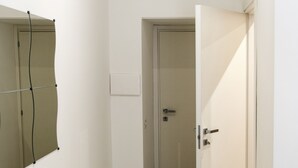 Un pasillo estrecho con suelo de madera, una puerta blanca y un aire acondicionado instalado en la pared.