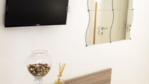 Una habitación moderna con un escritorio de madera, una silla, un televisor montado en la pared y un espejo.