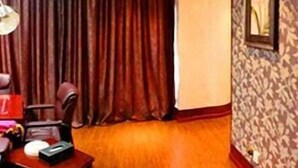 A hotel room with a wooden floor, a desk with a chair, a clock, and a framed picture on the wall. - Bo Jing International Hotel (Hangzhou)