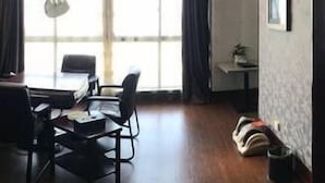 A modern room with a wooden floor, a dining table with chairs, a small side table, and a large window with curtains. - Bo Jing International Hotel (Hangzhou)