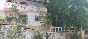 A multi-story building with a stone wall and a balcony with white balustrades.