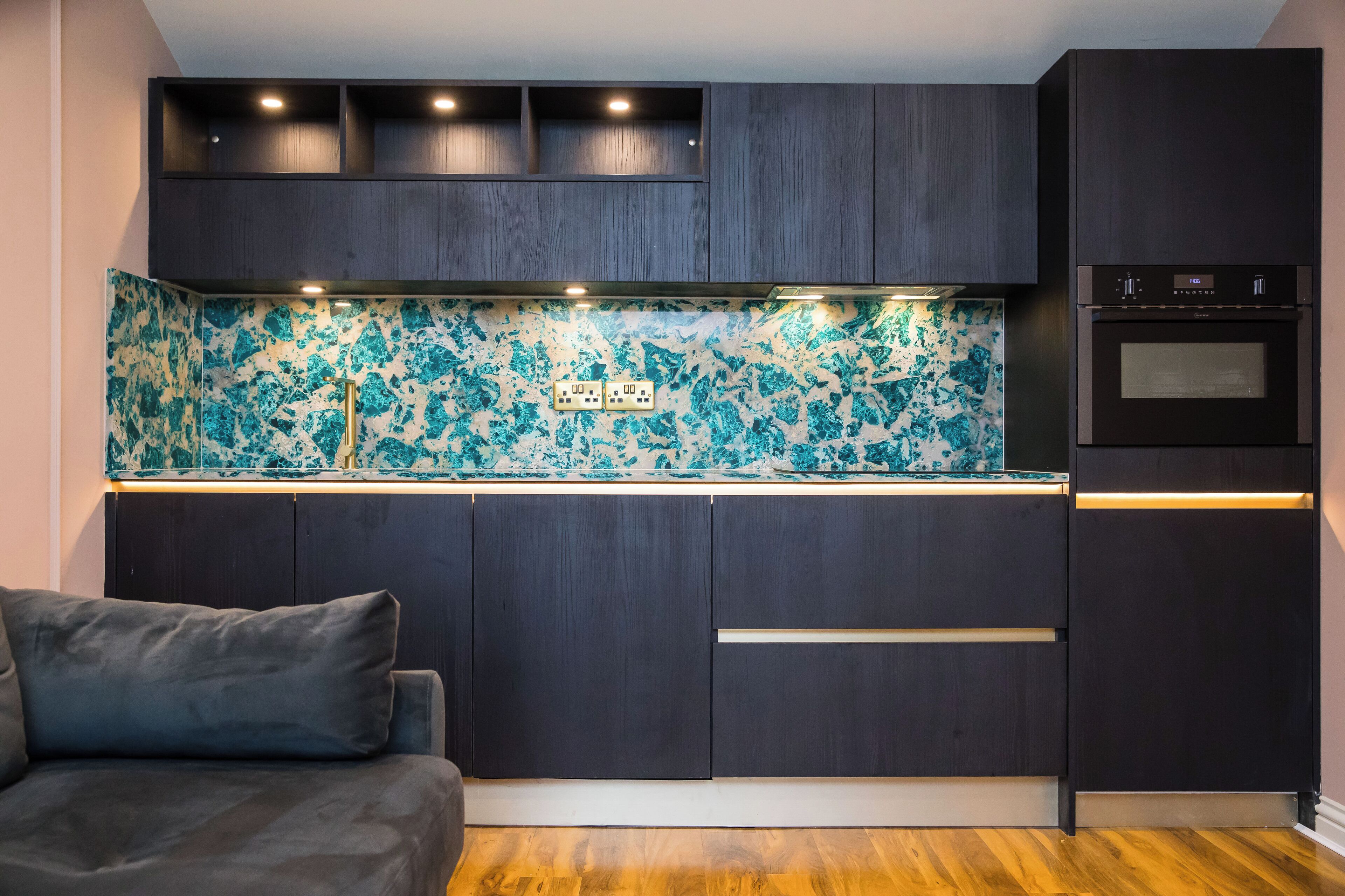 A modern kitchen with dark wood cabinets, a backsplash with a blue and white pattern, and built-in appliances.