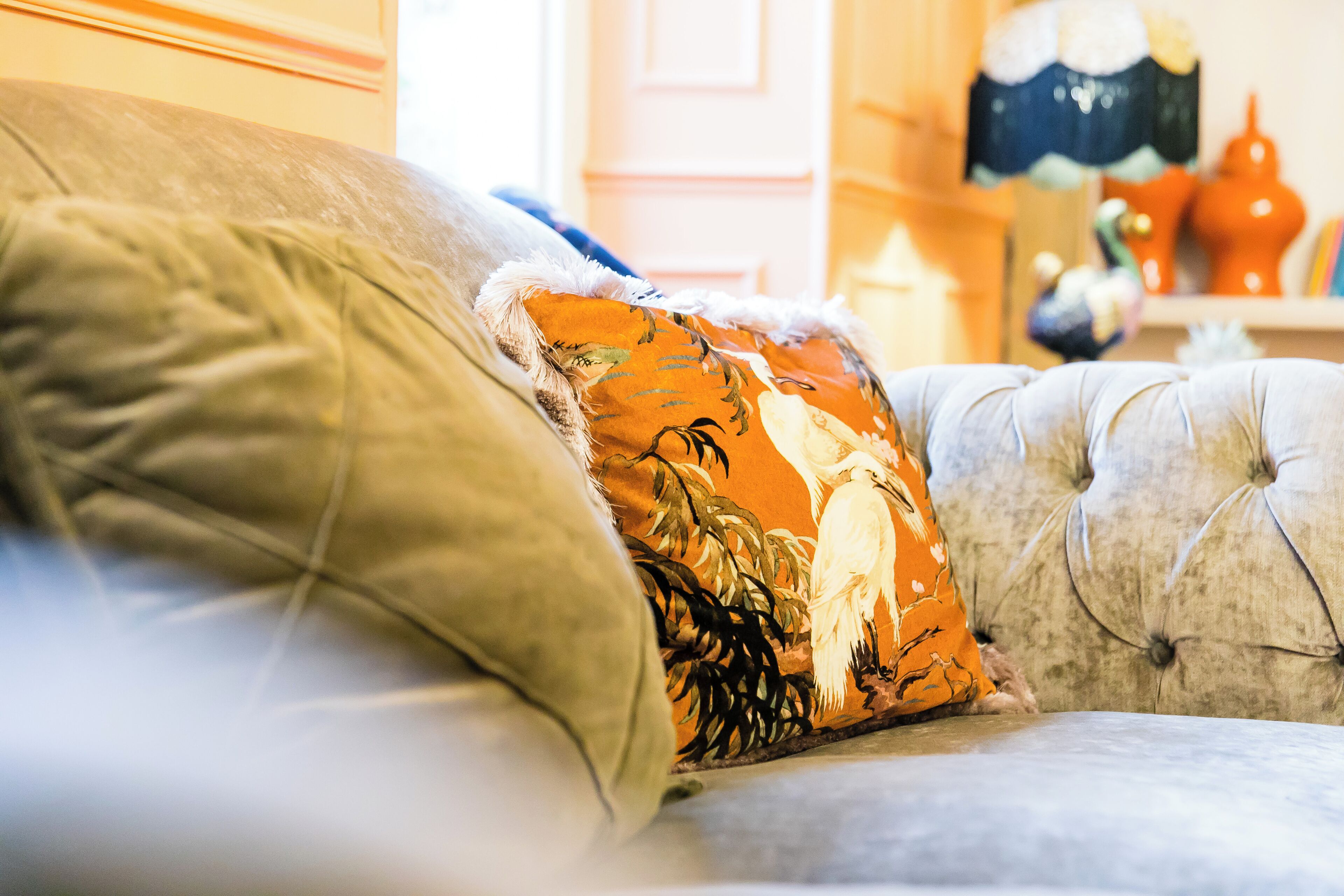 A tufted sofa with a floral pillow and a plain pillow.