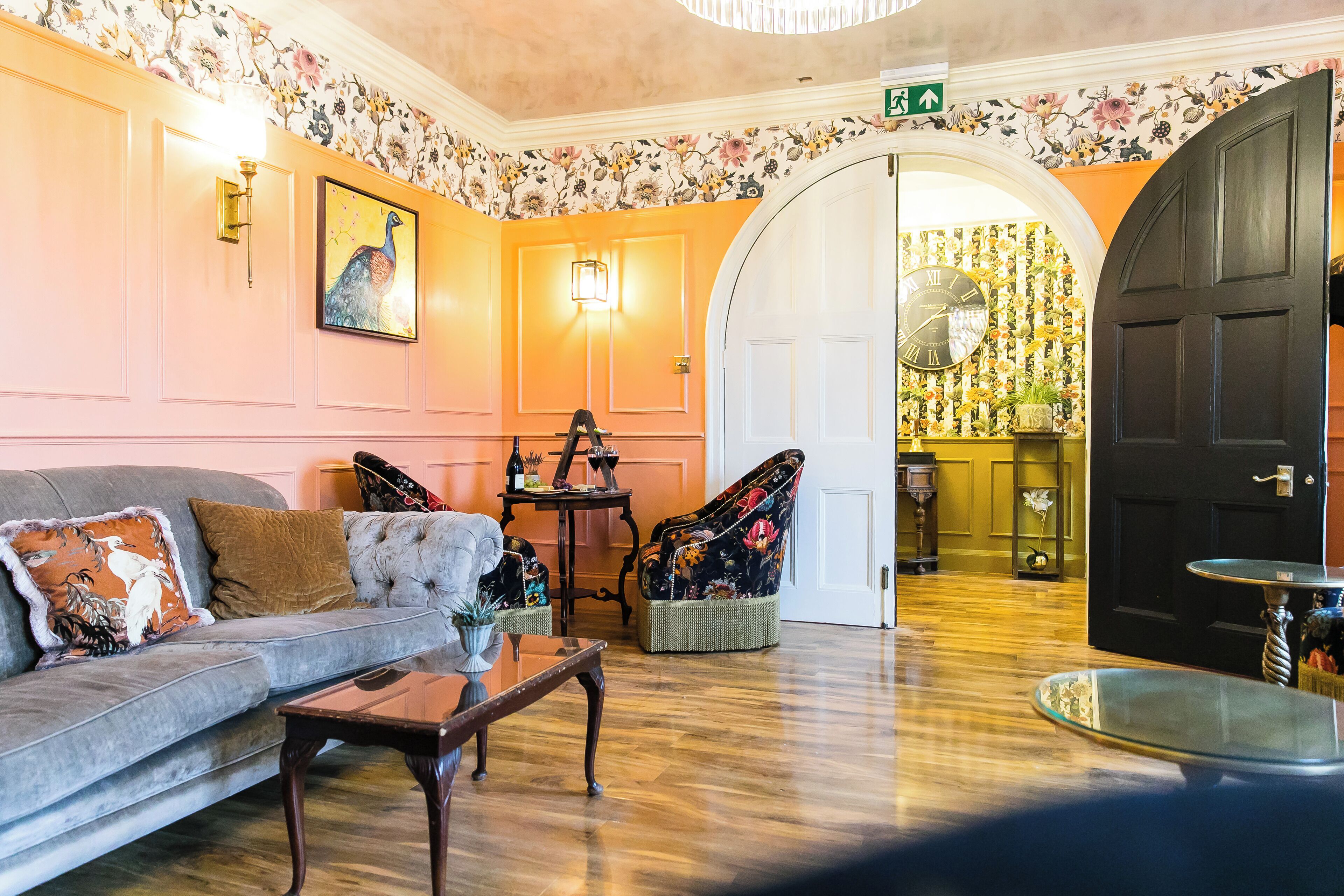 A room with a sofa, armchair, and a table with a lamp.