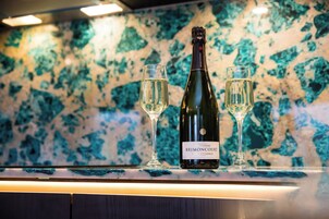 Una botella de champán Brimontcourt y dos copas sobre una encimera con salpicadero de mármol.
