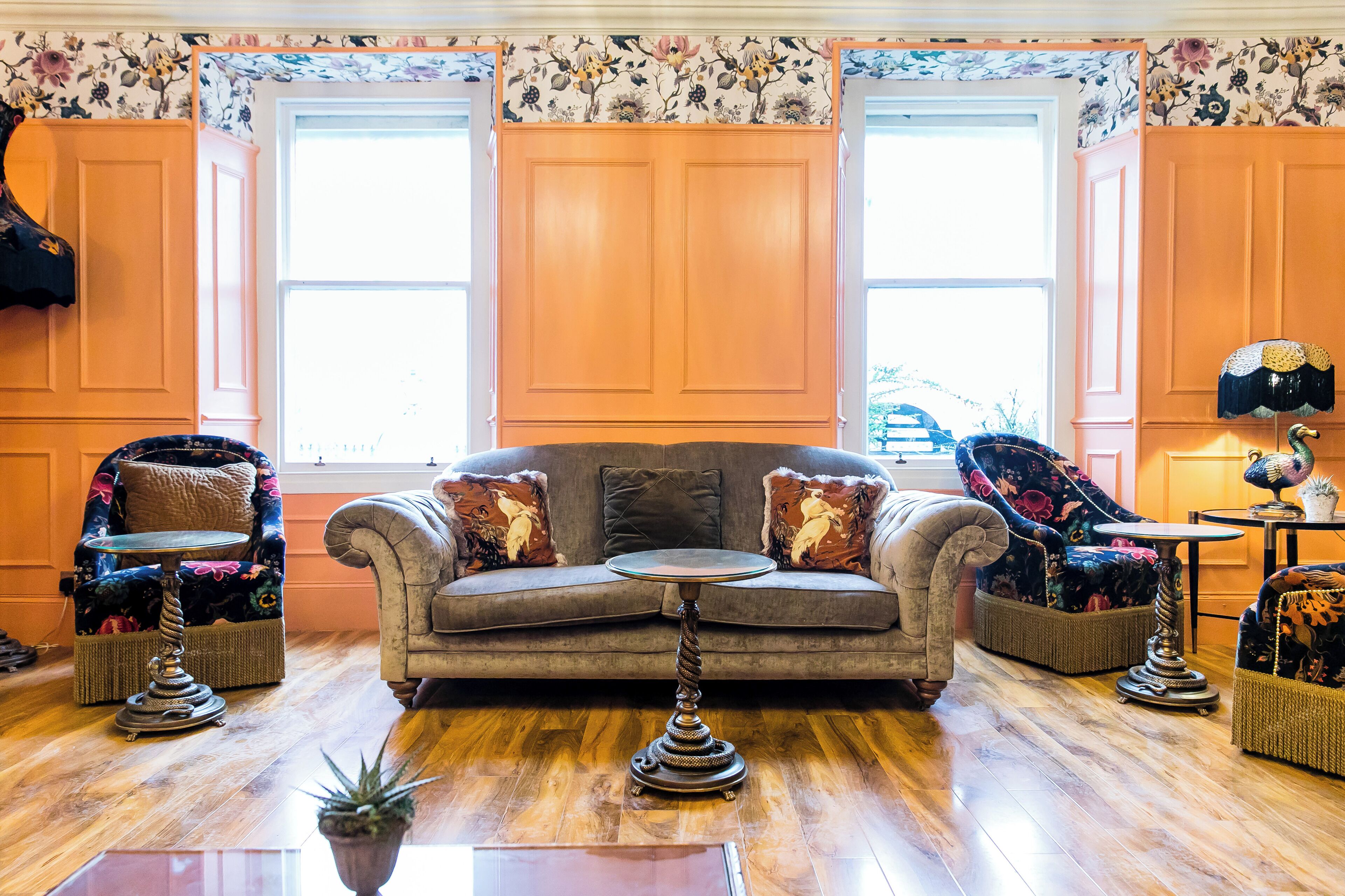 A cozy living room with a sofa, two armchairs, a small table, and a decorative lamp.