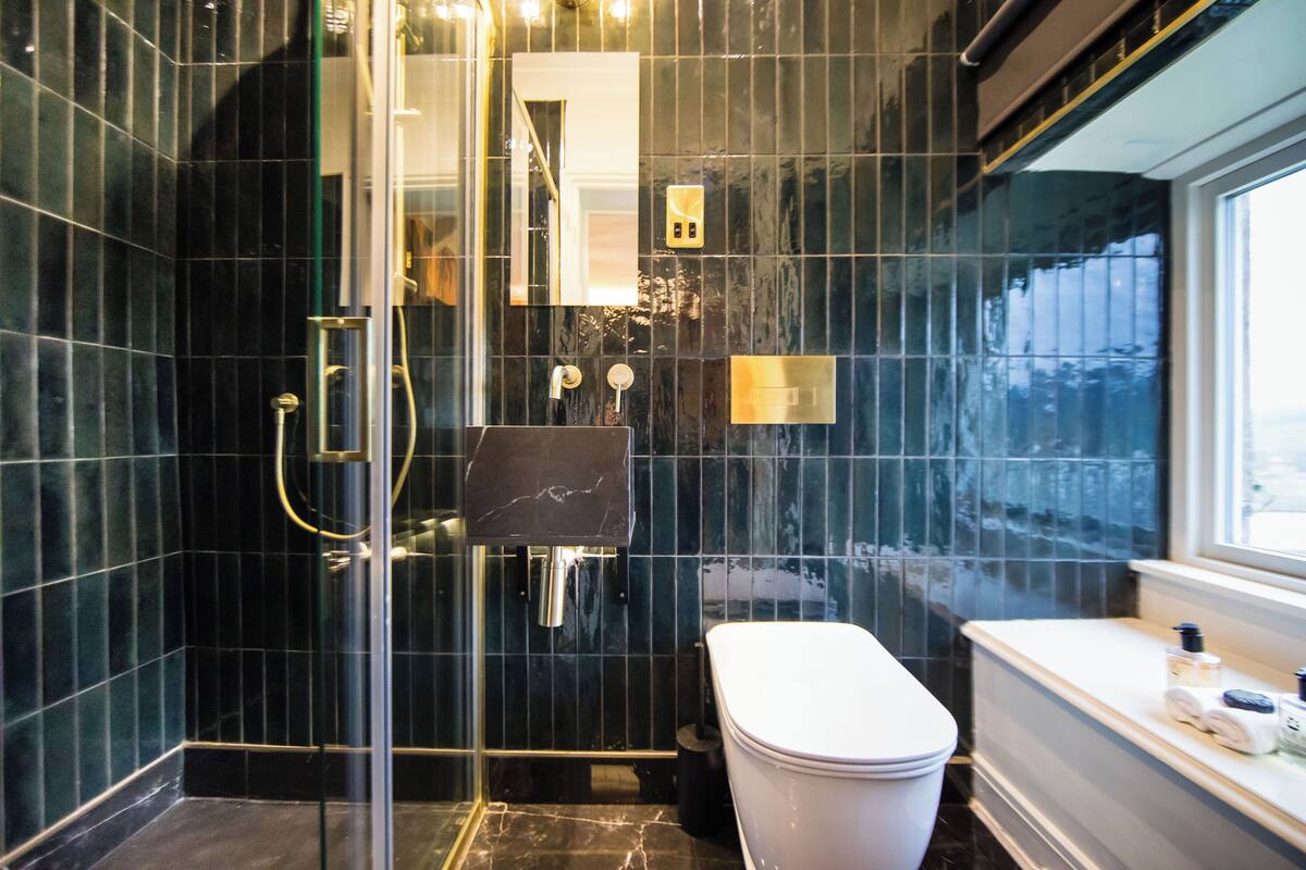 A modern bathroom with a glass-enclosed shower, a white toilet, and a vanity with a mirror.