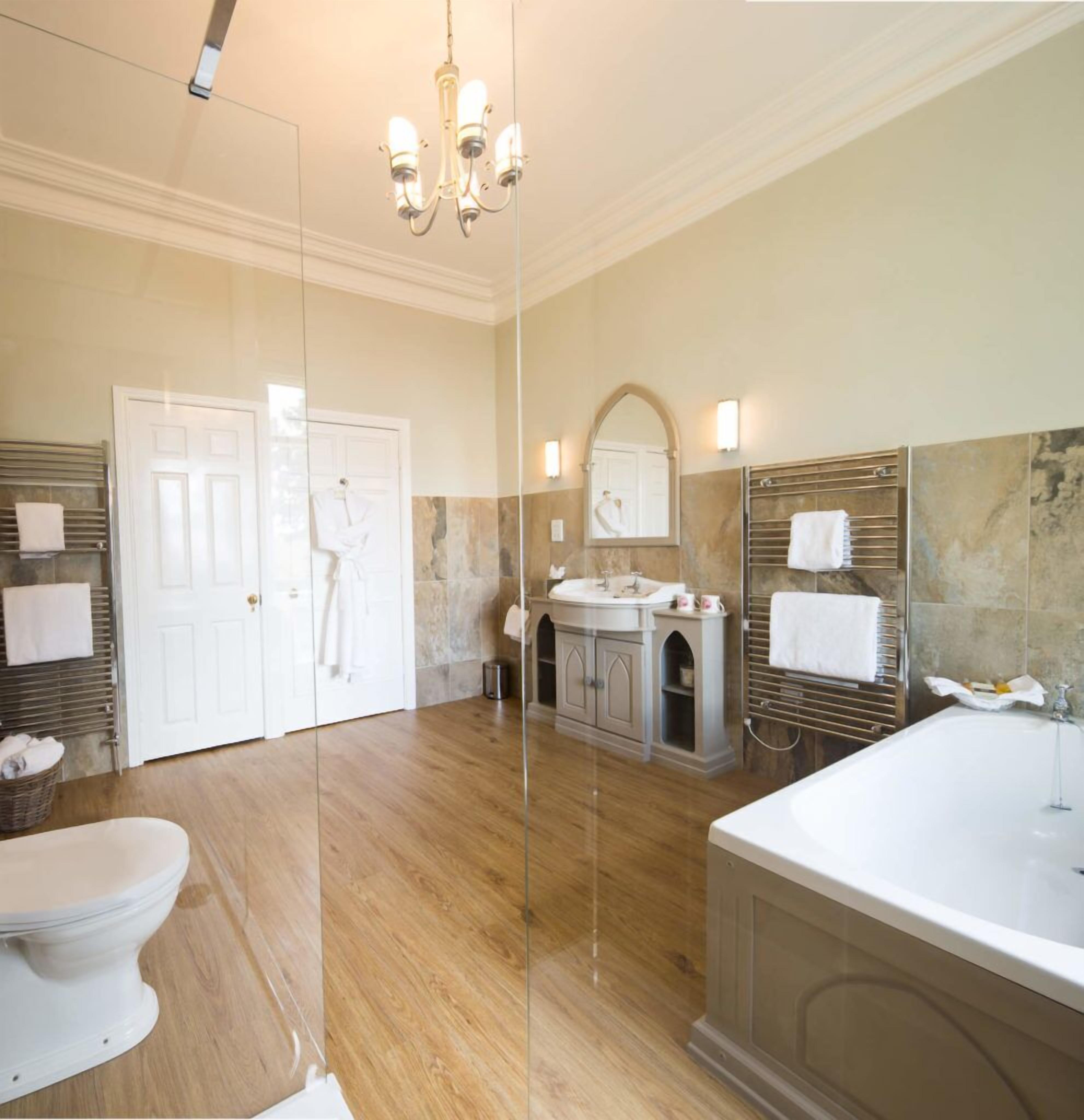 A modern bathroom with a large mirror, a bathtub, and a toilet.