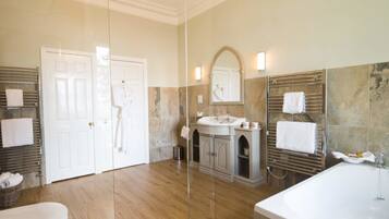 A modern bathroom with a large mirror, a bathtub, and a toilet.