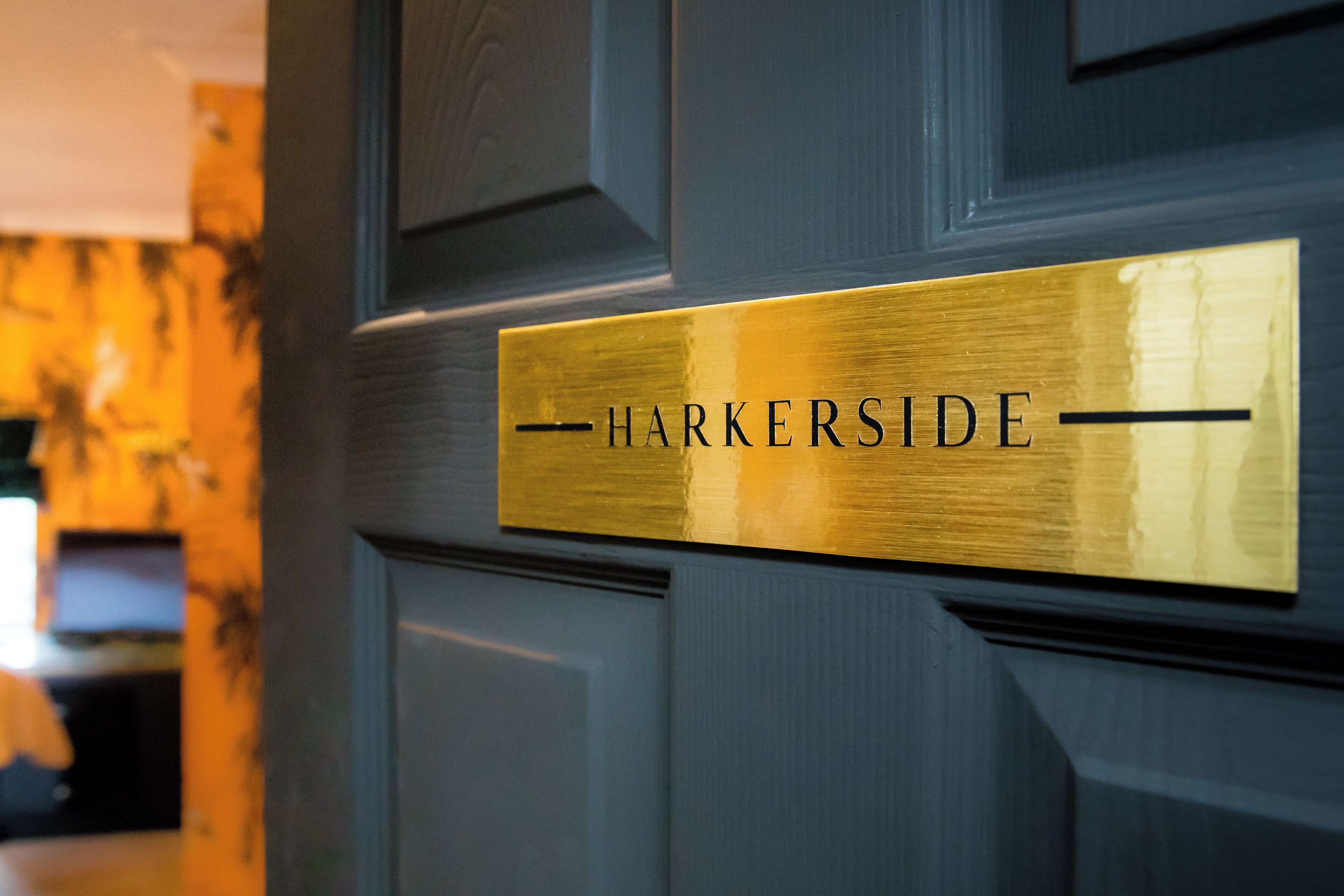 A gold plaque with the text "HARKERSIDE" on a dark wooden door.