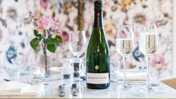 Una mesa dispuesta con una botella de champán Brut Regence de Brimacourt, dos copas y un arreglo floral.