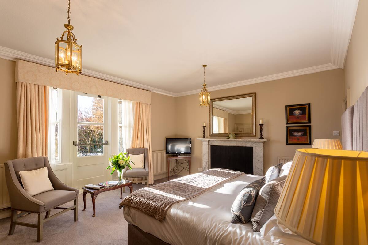 A hotel room with a large bed, a television, a fireplace, and a view of the outdoors.