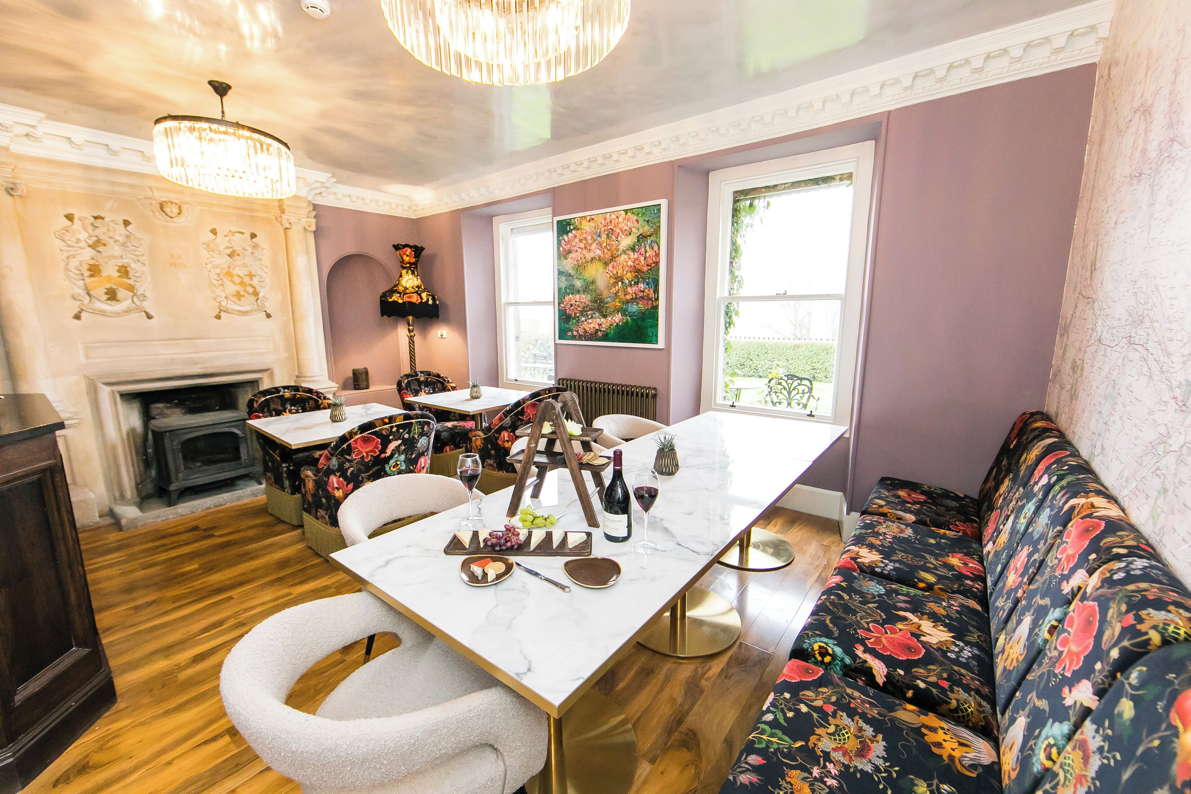 A dining area with a marble table, floral upholstery, and a fireplace.