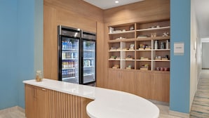 A modern kitchenette with two refrigerators, wooden cabinets, and a white countertop.