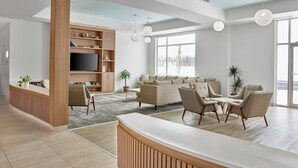 A modern living room with a wooden reception desk, a sofa set, and a television on a wooden cabinet.