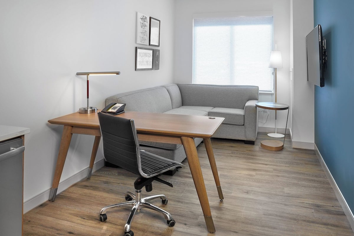A modern office space with a desk, chair, and sofa.