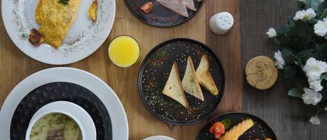 A breakfast setting with plates of food, including an omelet, toast, and soup.