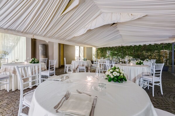 A banquet hall with round tables, white chairs, and floral centerpieces. - Europa Stabia Hotel (Castellammare di Stabia)