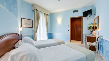 Habitación de hotel con dos camas, un escritorio, una silla, un televisor y una puerta.