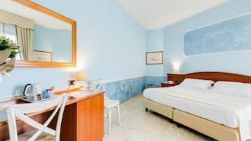 Quarto de hotel com cama, escrivaninha, cadeira e um espelho grande.