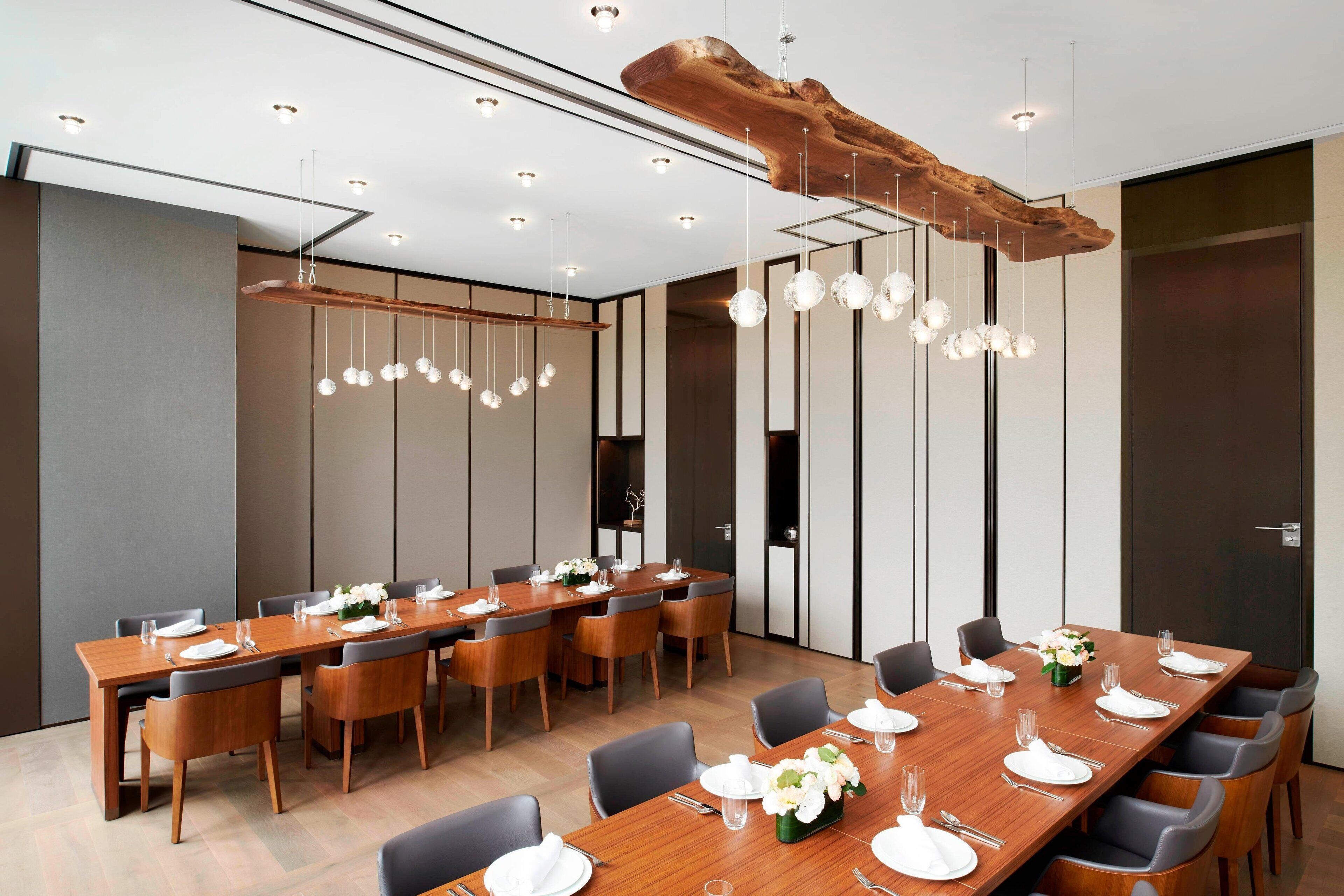 Ein moderner Konferenzraum mit einem langen Holztisch, der für ein Meeting gedeckt ist, umgeben von Stühlen.