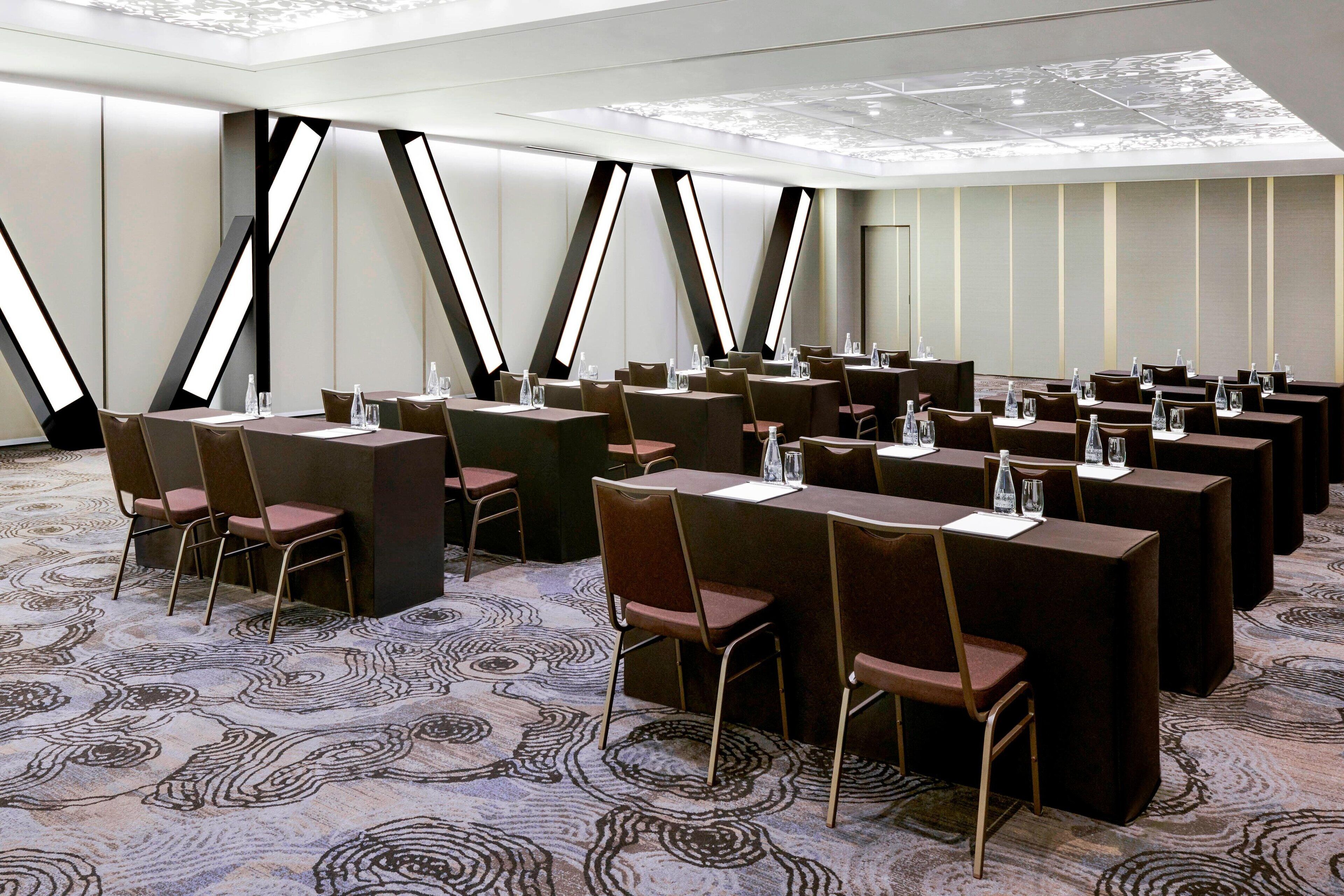 A conference room with multiple tables and chairs, equipped with water bottles and notepads.