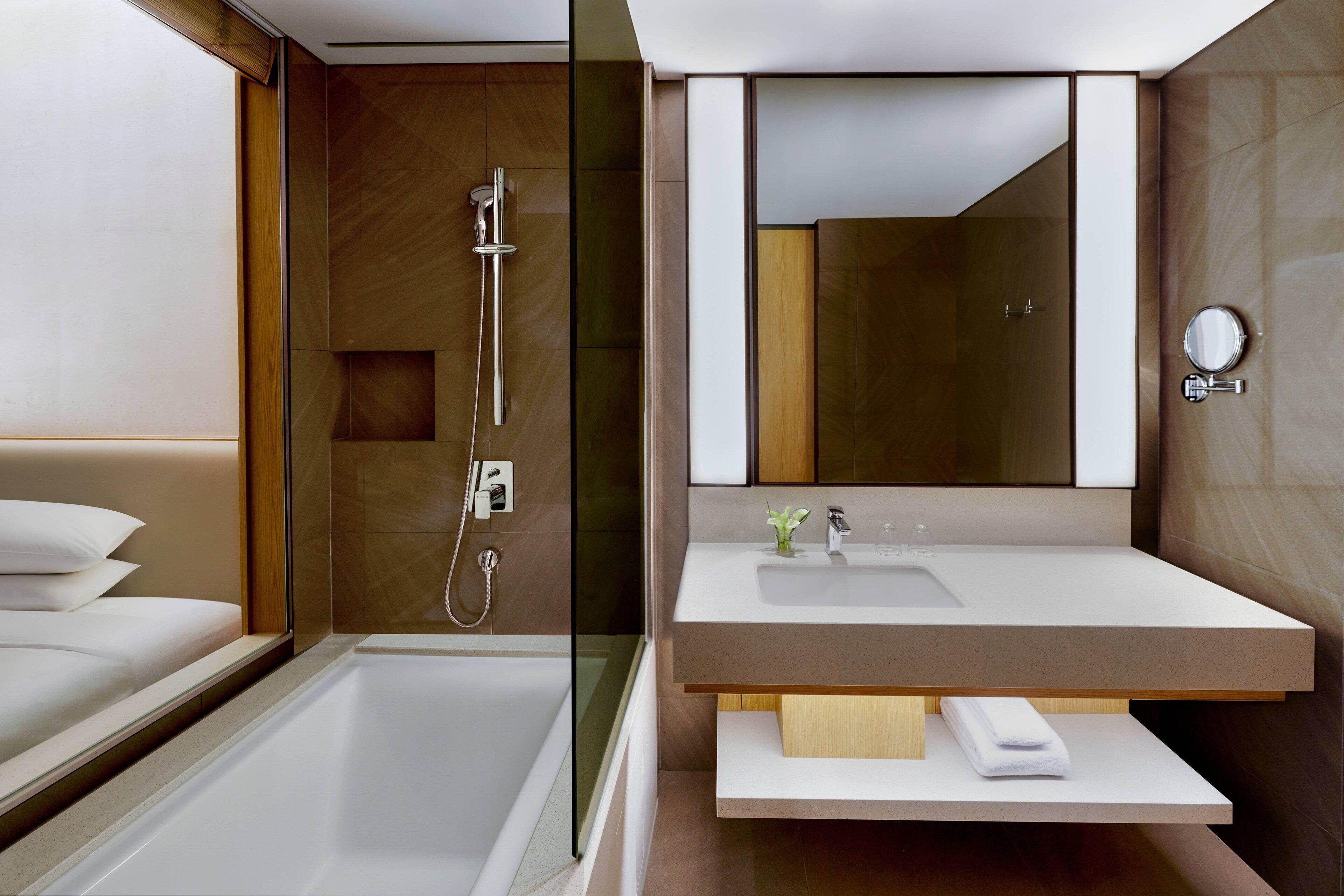 A modern bathroom with a bathtub, shower, and vanity with a mirror.