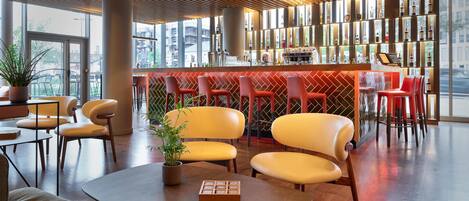 A modern bar area with wooden slatted ceiling, red bar stools, and a variety of bottles on shelves.