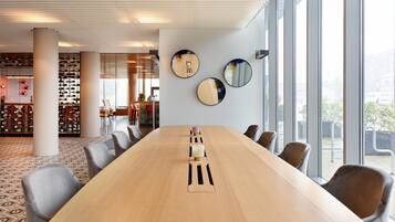 A conference room with a long table, chairs, and large windows.