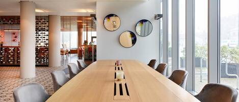 A conference room with a long table, chairs, and large windows.