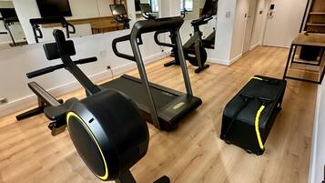 Et fitnessrum med løbebånd, motionscykel og romaskine.