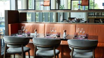 Um restaurante com interior moderno, com assentos de couro, balcão e vista pela janela ampla.
