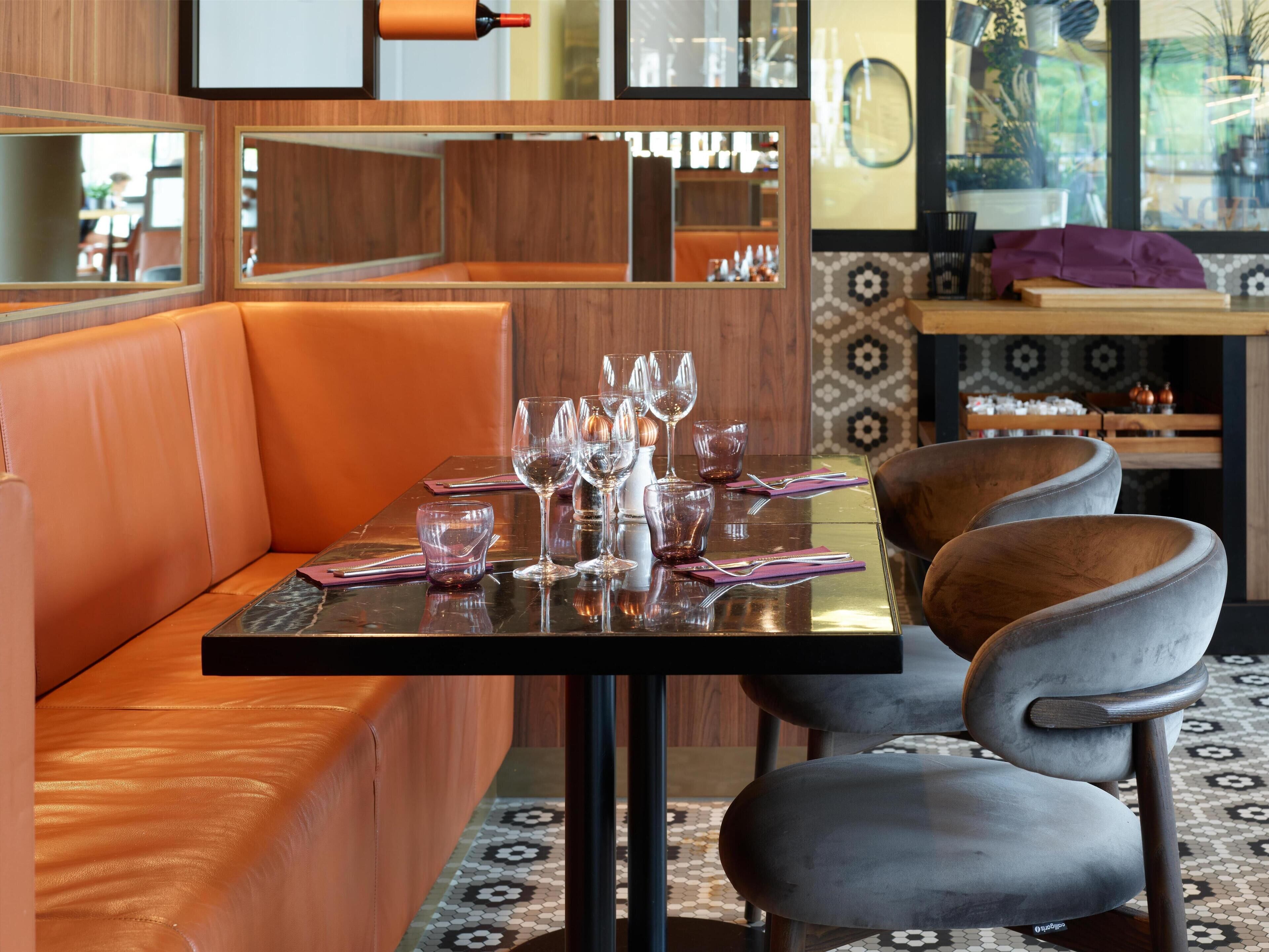 Un restaurante con una zona de cabinas, una mesa lista para comer y una barra al fondo.