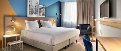 Una habitación de hotel moderna con una cama grande, un escritorio, una silla y un televisor.