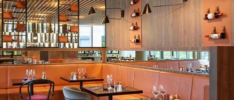 A modern restaurant interior with wooden ceiling, leather booths, and wine bottles on the wall.